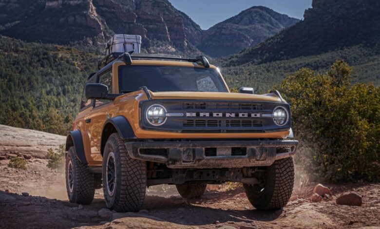 A yellow Ford Bronco midsize SUV is driving off-road.