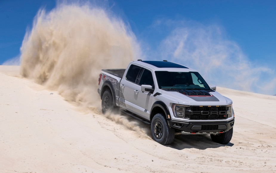 A white Ford F-150 Raptor R 2023 drives on the sand dunes. These are the toughest off-road trucks on the market.