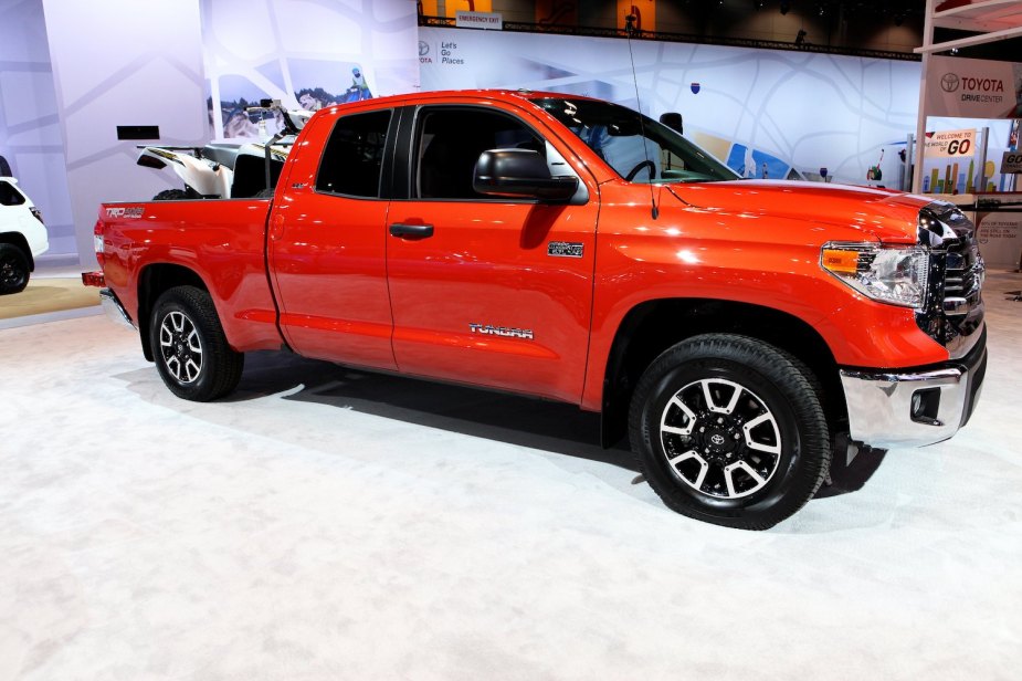An orange 2017 Toyota Tundra parked at a motor show, SUV in its bed.