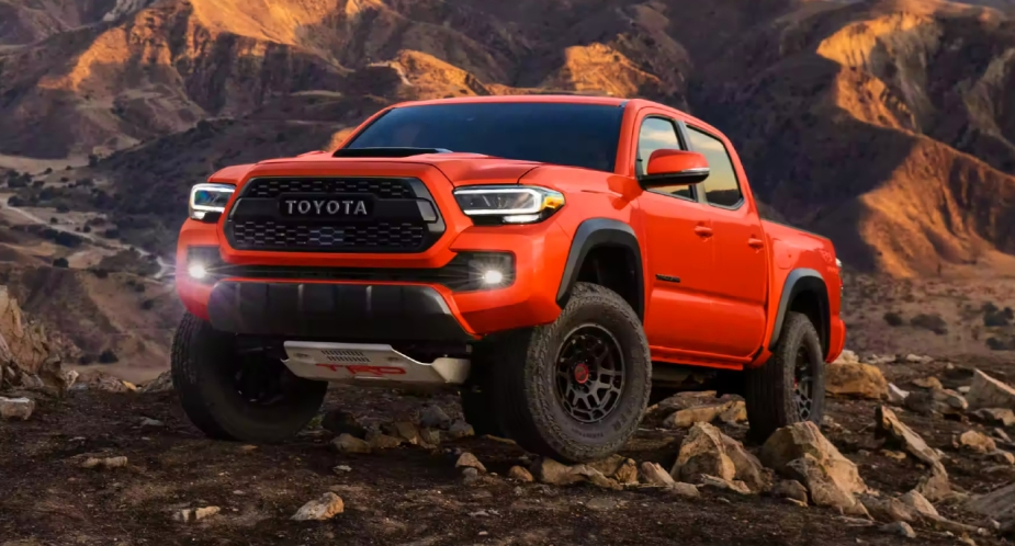 An orange 2023 Toyota Tacoma pickup truck parked off-road.