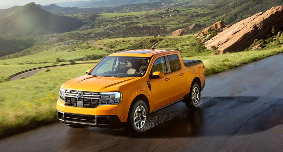 A yellow 2023 Ford Maverick pickup truck driving on a wet road. 