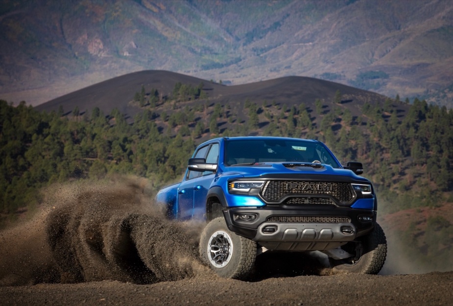 A blue Ram TRX skidding off-road, mountains and a cloud of dust appearing in the background.