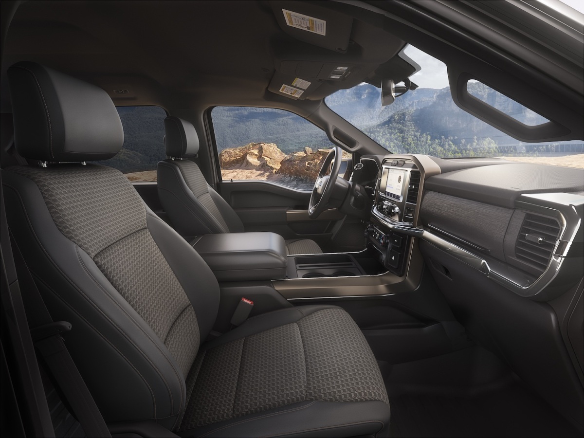 The interior of the entry-level Ford F-150 XL has cloth seats, a mountain range is visible outside the window.