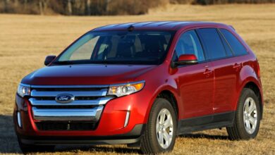 A red 2012 Ford Edge parked outside on grass, it