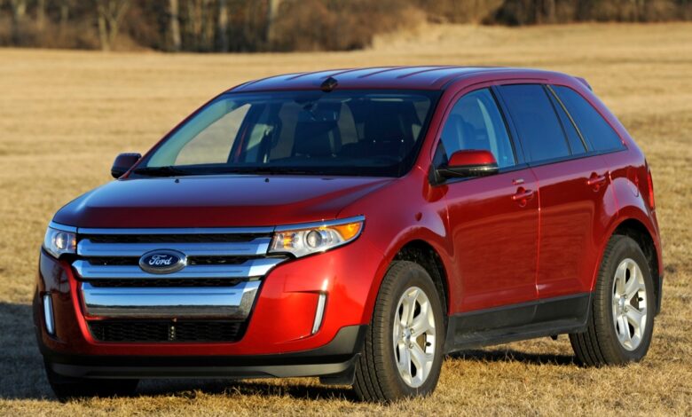 A red 2012 Ford Edge parked outside on grass, it