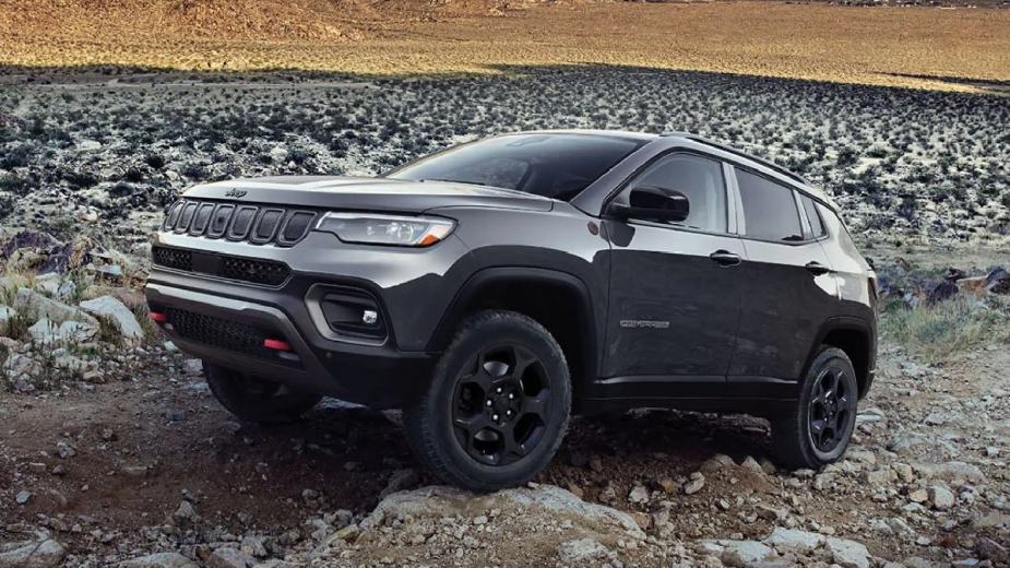 Gray 2023 Jeep Compass small SUV, the new cheapest Jeep, drives on rocky terrain