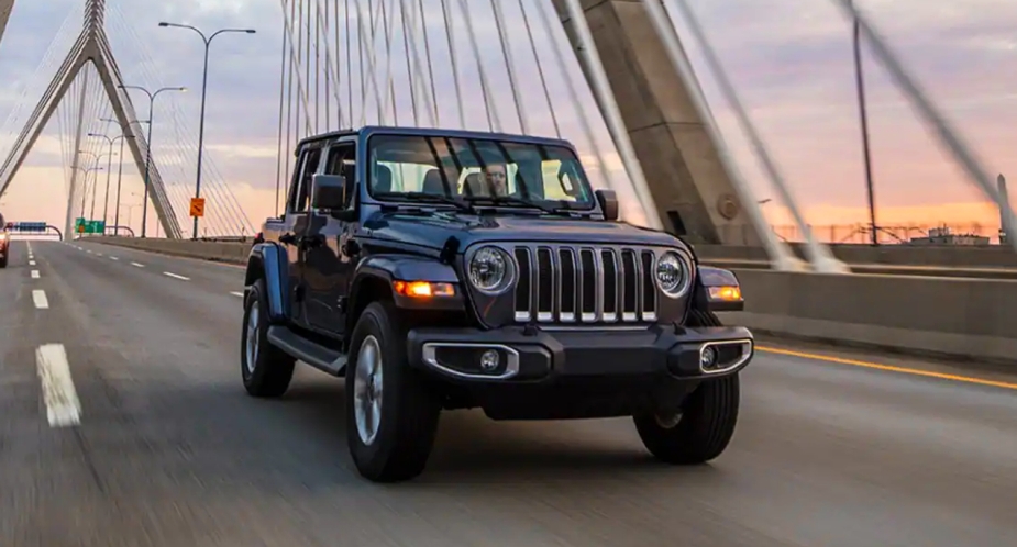 A blue 2023 Jeep Wrangler SUV is driving on the road.