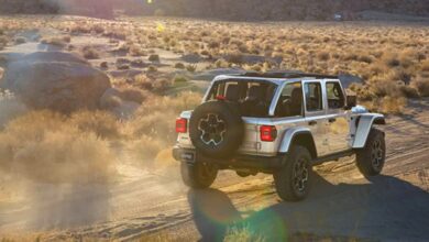A gray 2023 Jeep Wrangler small SUV is driving off-road.