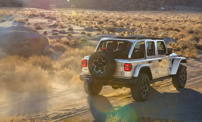 A gray 2023 Jeep Wrangler small SUV is driving off-road.