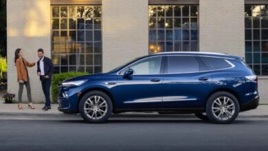 A dark blue 2023 Buick Enclave three-row midsize luxury crossover SUV side profile shot