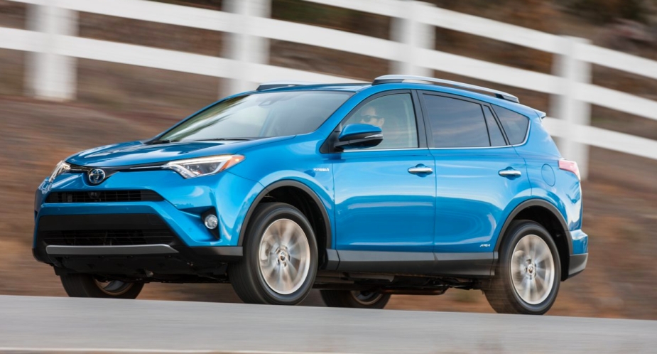 A blue 2016 Toyota RAV4 Hybrid small SUV is driving on the road. 