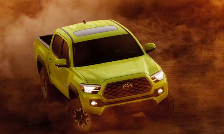 A green Toyota Tacoma midsize pickup truck is driving off-road.