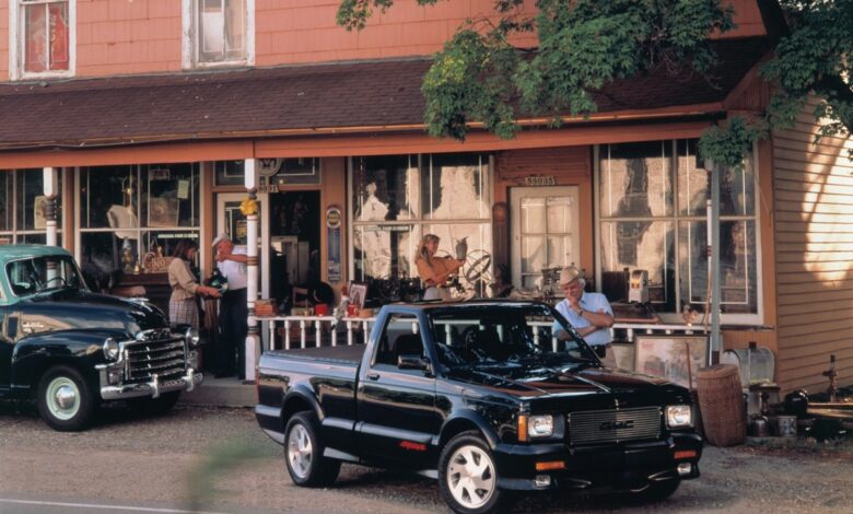 Black 1991 GMC Syclone pickup truck parked in front of an old building.