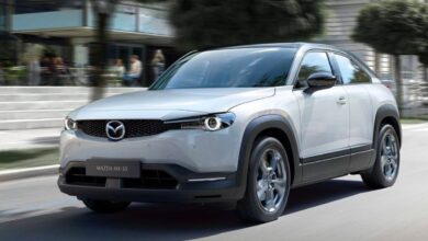 A gray Mazda CX-30 subcompact electric SUV is driving on the road.