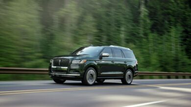 2022 Lincoln Navigator Manhattan Green Black Label full-size luxury SUV driving on a forest highway
