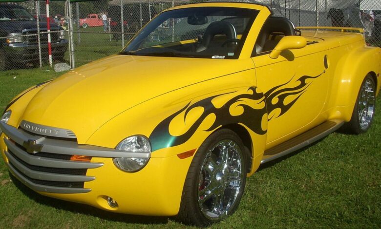 A yellow Chevy SSR pickup truck with flames on its side.