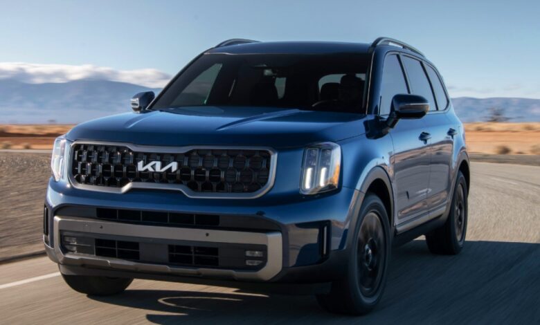 A blue Kia Telluride midsize SUV is driving on the road.