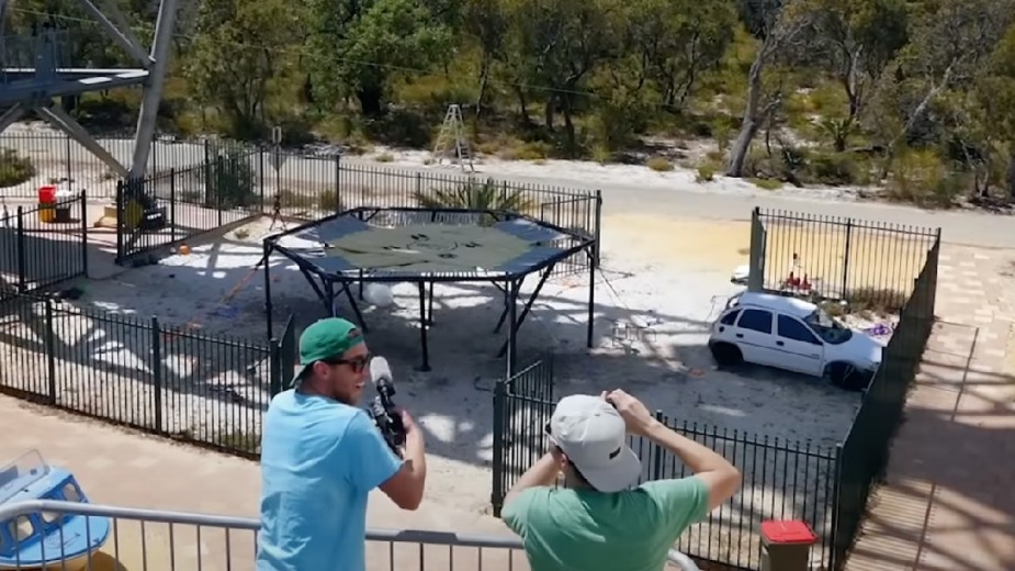 Mark Robert and another man celebrate after the car survives jumping on a trampoline