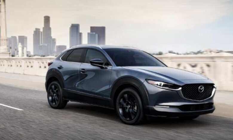 A blue 2023 Mazda CX-30 subcompact SUV is driving on the road.