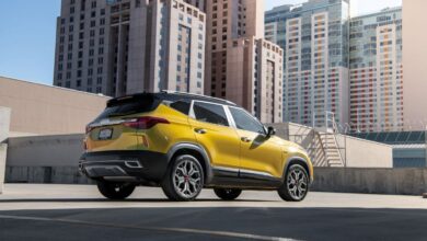 A yellow 2023 Kia Seltos subcompact SUV model parked on a rooftop shaded by skyscrapers