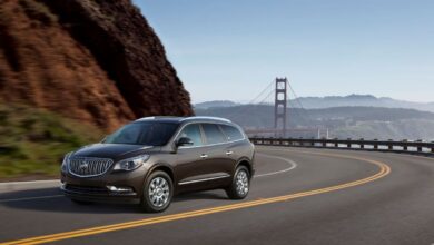 A dark brown 2013 Buick Enclave three-row luxury SUV model driving on a highway near the Golden Gate Bridge