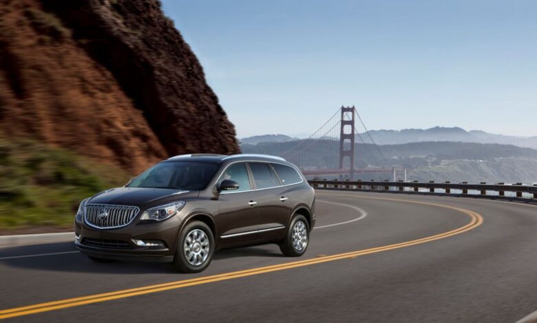 A dark brown 2013 Buick Enclave three-row luxury SUV model driving on a highway near the Golden Gate Bridge