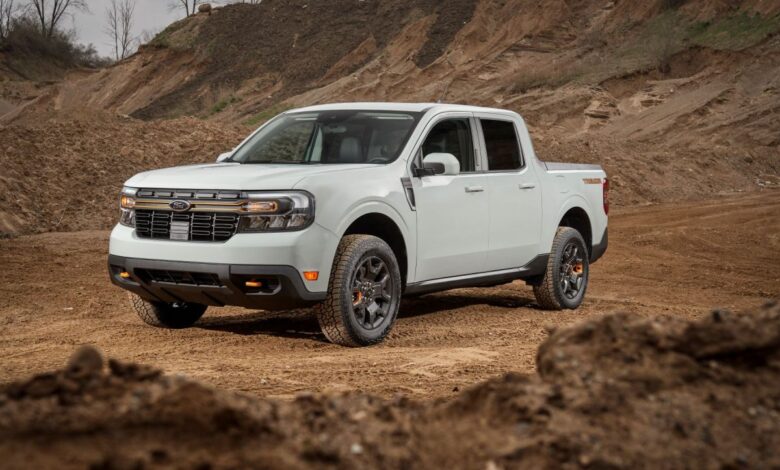A white 2023 Ford Maverick Tremor compact pickup truck model parked near mounds of plowed dirt at a worksite