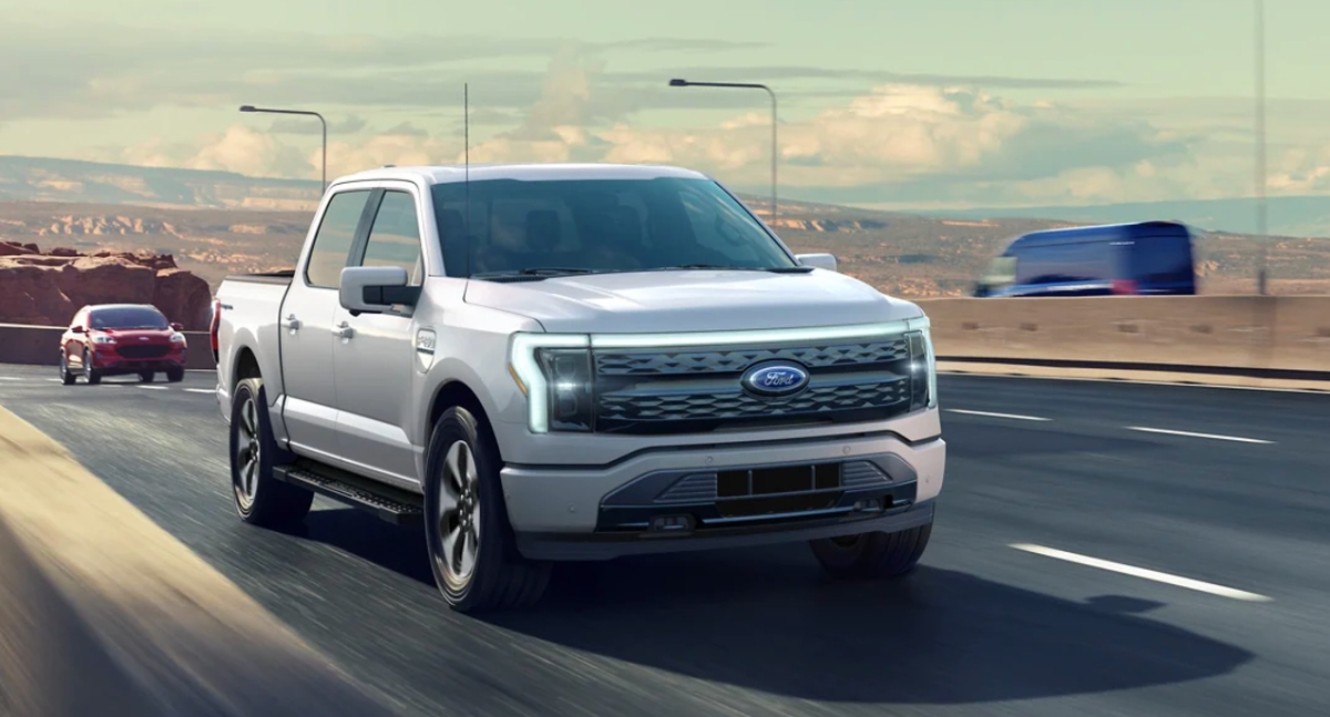 A gray Ford F-150 Lightning electric pickup truck is on the road.