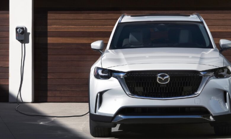 A white 2024 Mazda CX-90 PHEV midsize plug-in hybrid SUV is charging.
