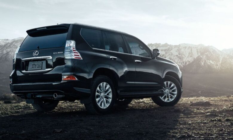 A rear side profile shot of a black 2023 Lexus GX 460 full-size luxury SUV model parked on a dirt cliff