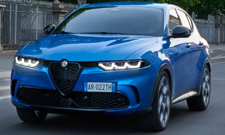 A blue 2023 Alfa Romeo Tonale small luxury plug-in hybrid SUV is driving on the road.
