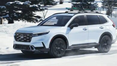 A white 2023 Honda CR-V small SUV is driving in the snow.