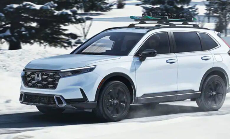 A white 2023 Honda CR-V small SUV is driving in the snow.