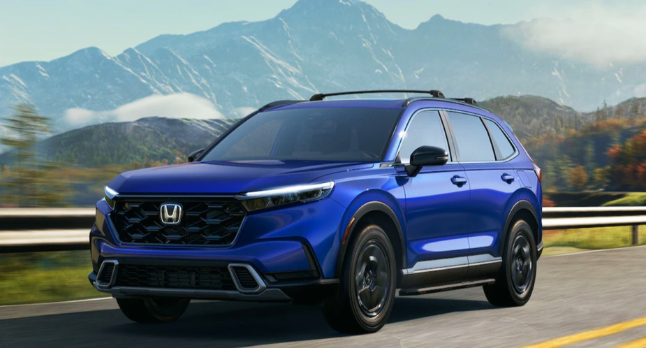 A small blue 2023 Honda CR-V SUV is driving on the road. 