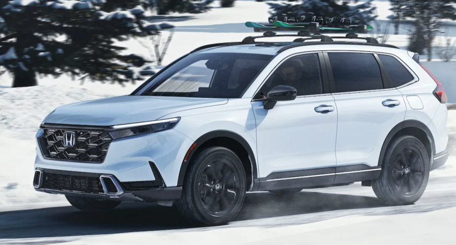 A small white 2023 Honda CR-V SUV is driving in the snow. 