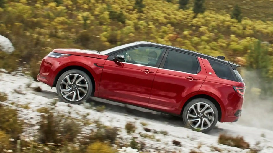 Side view of red 2023 Land Rover Discovery Sport, the new cheapest Land Rover and off-road luxury SUV bargain