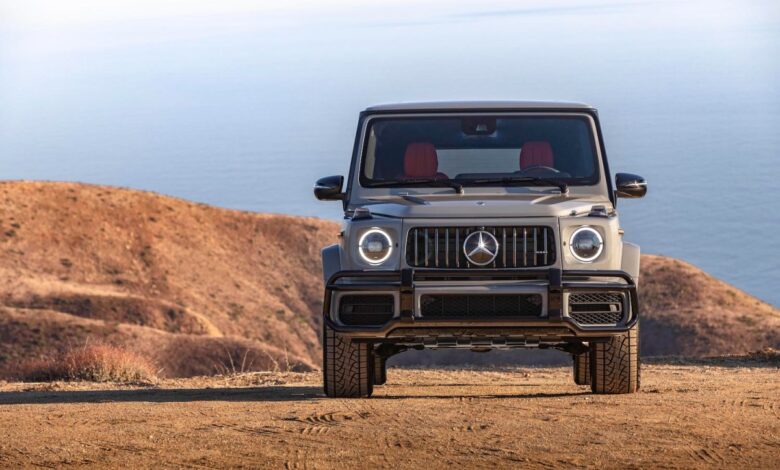This is a promo photo of a 2021 G Class SUV parked on a sand dune in front of the ocean.