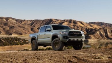 A 2023 Toyota Tacoma Trail Edition midsize pickup truck parked on a field of plowed dirt