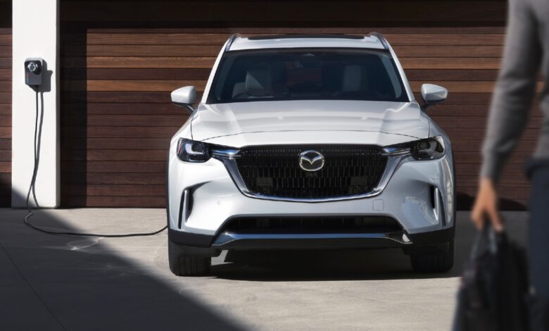 A white 2024 Mazda CX-90 PHEV midsize SUV is charging.