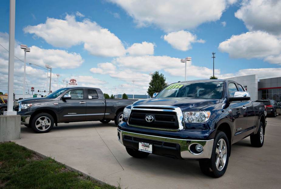 Two second-generation Toyota Tundra pickups parked at a yard sale, price stickers on their windows.