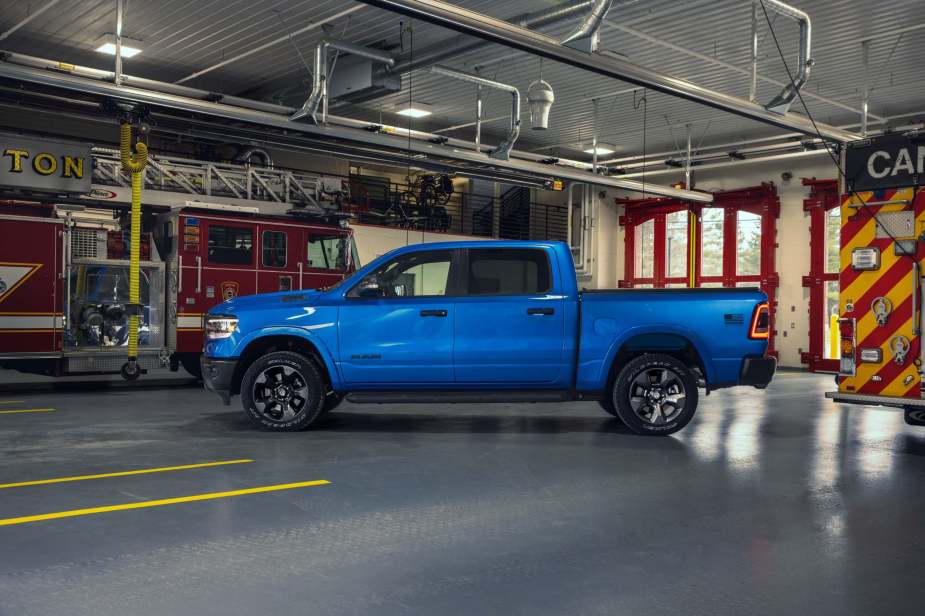 Side view of a bright blue Ram 1500 Longhorn with crew cab configuration parked in a fire station.