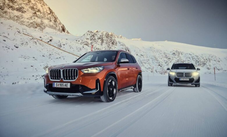 Orange and gray BMW X1 xDrive23d and XDrive30 models driving through the snow near mountains