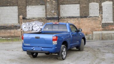 The rear of a blue 2007 Toyota Tundra parked in front of a brick wall with grafitti.