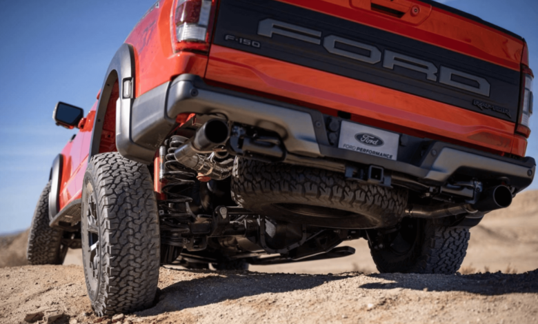 A rear and undercarriage shot of a 2023 Ford F-150 Raptor full-size pickup truck model driving over dirt hills