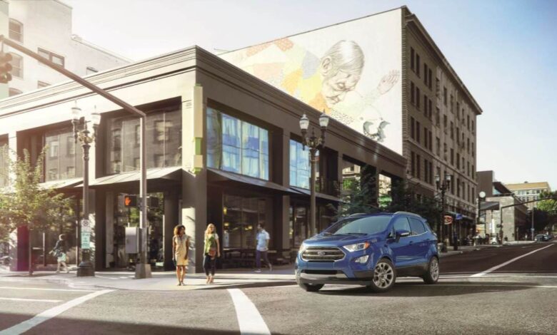 A blue 2022 Ford EcoSport subcompact crossover SUV model stopped at a crosswalk