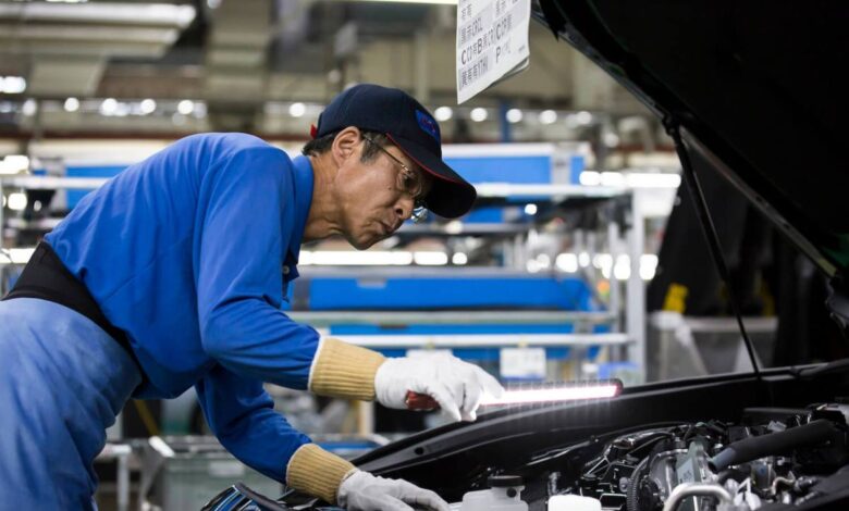 A Toyota factory worker inspects a vehicle to ensure the company