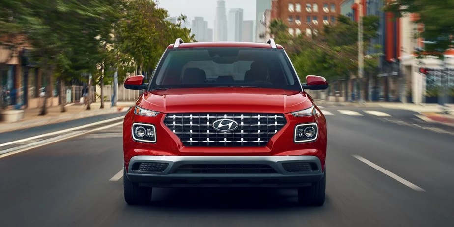 A red 2023 Hyundai Venue compact SUV is driving on the road. 