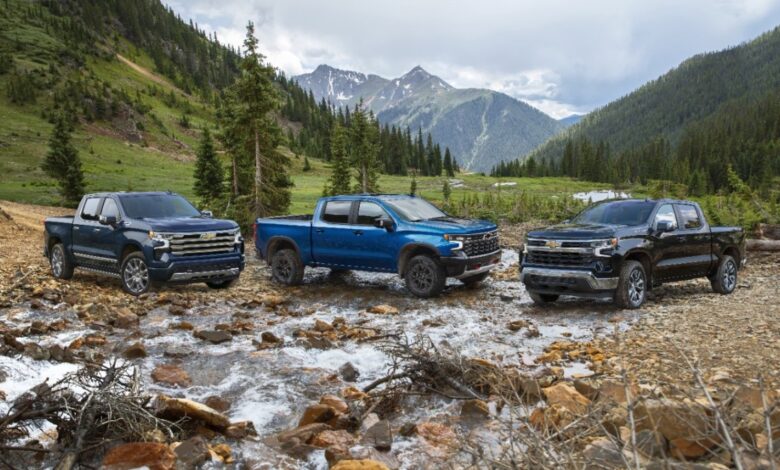 A lineup of different 2023 Chevy Silverados on a riverbed.