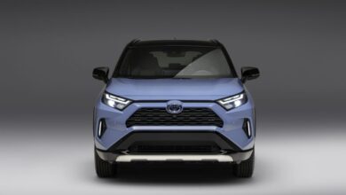 Press photo of a blue 2023 Toyota RAV4 front end in a white space.