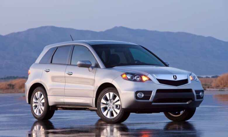 A silver-gray 2010 Acura RDX compact luxury crossover SUV model parked on a wet asphalt lot